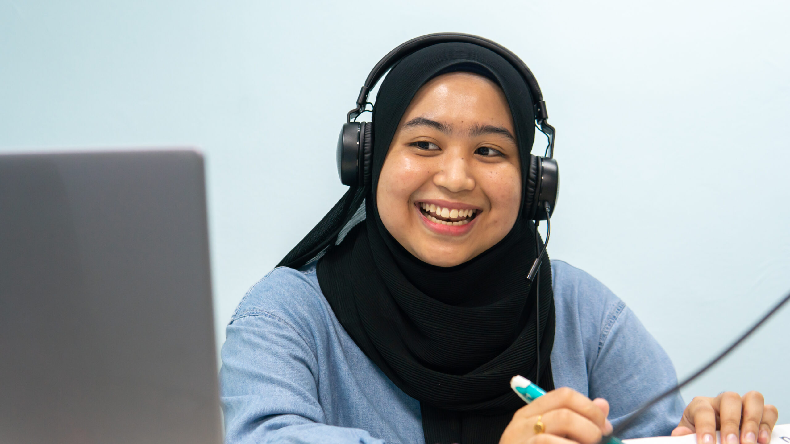 Cikgu Minda Optima tersenyum semasa sesi pengajaran dalam talian.