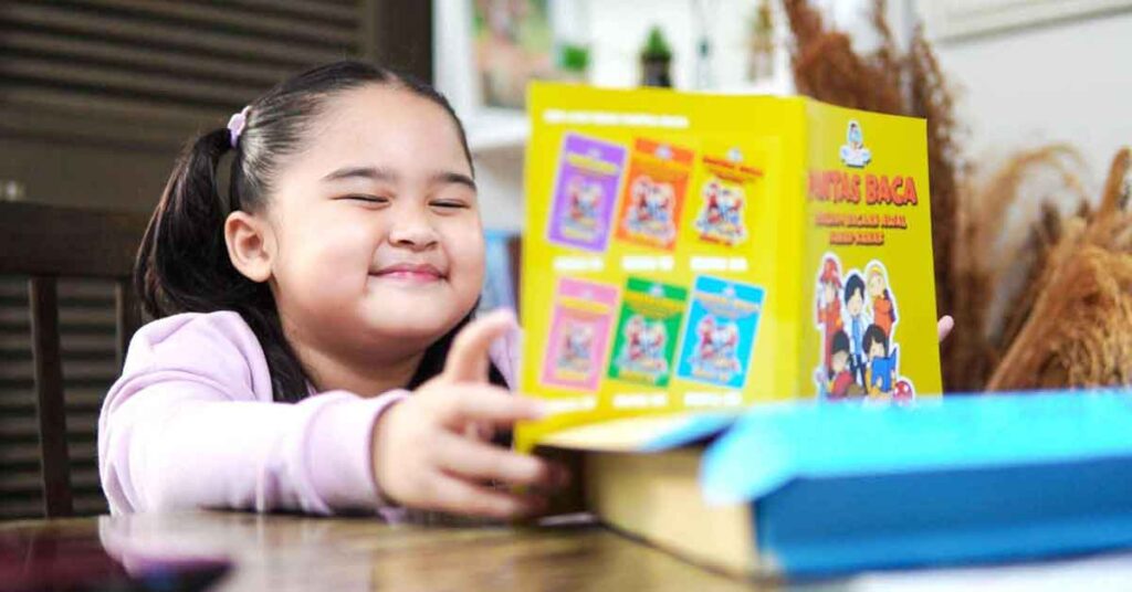 Budak perempuan sedang membaca buku dengan ceria di dalam kelas Pantas Baca
