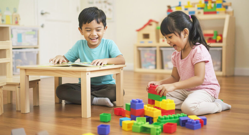 Dua orang anak sedang membaca bersama di meja belajar dan kemudian bermain blok binaan berwarna-warni, menunjukkan keseimbangan belajar dan bermain.